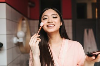 Lady in great mood doing day makeup. Brunette girl smiling on background of bathroom