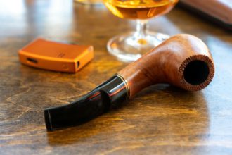 Smoking pipe on wooden office desk. Tobacco smoking habit