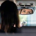 the beautiful eyes of the young driver woman are reflected in the rear view mirror